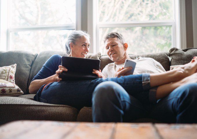 Couple looking at laptop and phone smiling